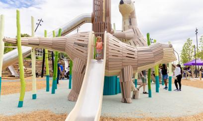 Toddler in orange onesie playing on giant otter slides at Tom Lee Park