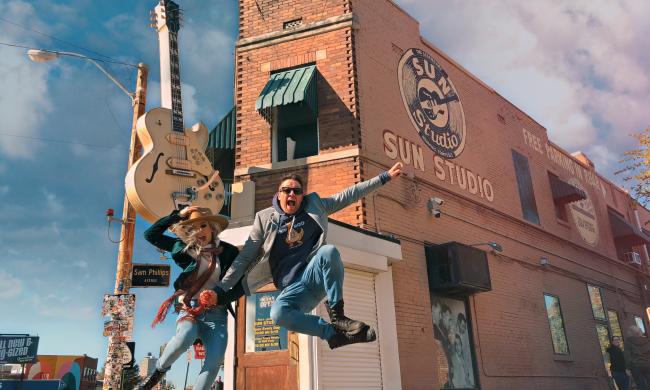 two people jump in the air in front of sun studio