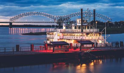 riverboat on Mississippi River with M bridge lit up in background
