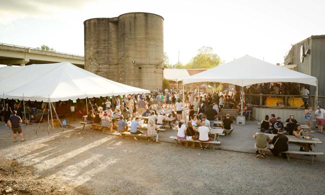 People gathered at picnic tables and under tents at Taste the Rarity beer festival at Wiseacre Brewing Co.