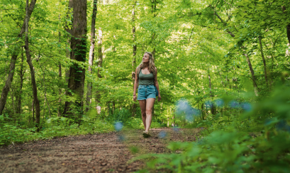 woman walks through green forest