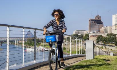woman rides along riverfront on bike