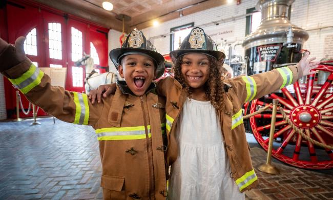 Two children dressed as firefighters at the Fire Museum of Memphis.