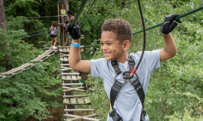 young boy walks across rope bridge