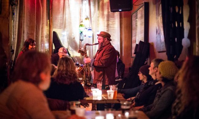 man plays saxophone inside bar dkdc