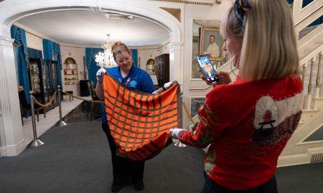 graceland curator holds up blanket for guests to touch inside graceland
