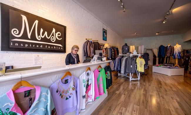 inside MUSE clothing store in south main. woman working behind desk with clothes on racks