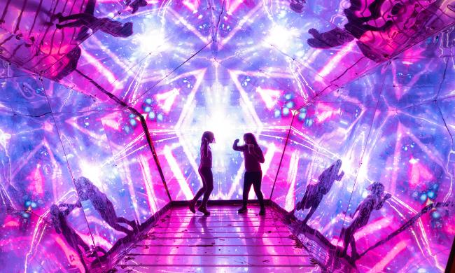 Two people dancing and enjoying the reflective light displays at Memphis Zoo Lantern Festival.