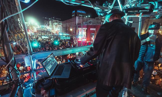 A DJ playing a set from a booth overlooking a crowd celebrating New Year's Eve on Beale Street.