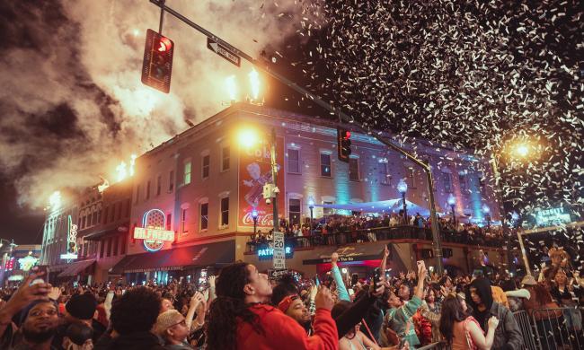Crowd celebrating New Year's eve on Beale Street as confetti falls from the sky.