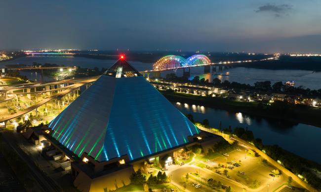 An aerial view of the Pyramid with the Mighty Lights lit up in rainbow on the Hernando De Soto Bridge.