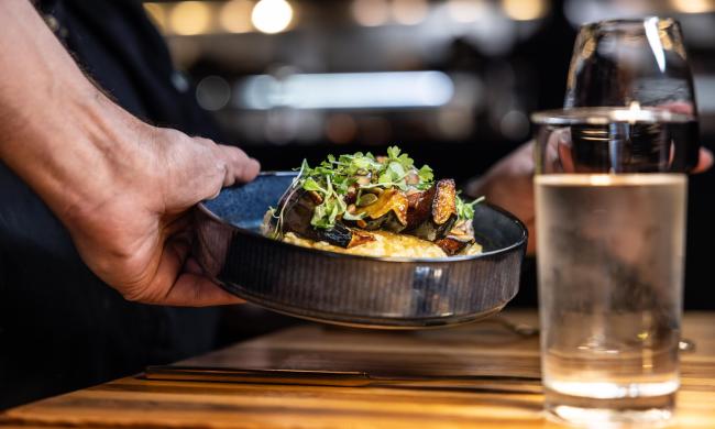 A plate being place on a table with glasses at The Lobbyist.