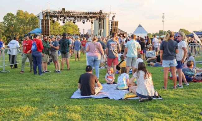 Festivalgoers at Grind City Fest at Grind City Brewery with a stage and the Memphis Pyramid in the background.