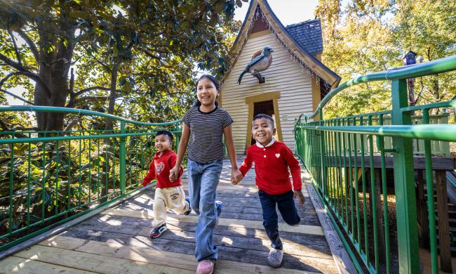 three kids holding hands, running, smiling having fun outdoors