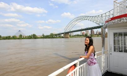A passenger enjoying a sightseeing riverboat tour with Memphis' Pyramid and Hernando de Soto bridge in the background