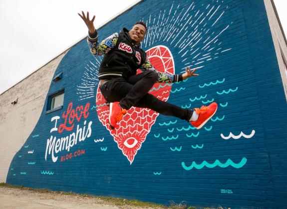 Memphis jookin dancer leaping in front of a mural