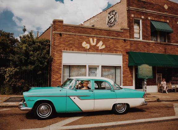 vintage blue car parked in front of sun studio