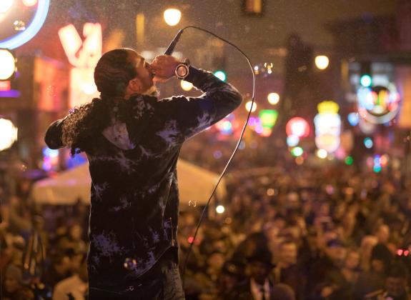 man performs on stage in front of huge crowd on new years eve
