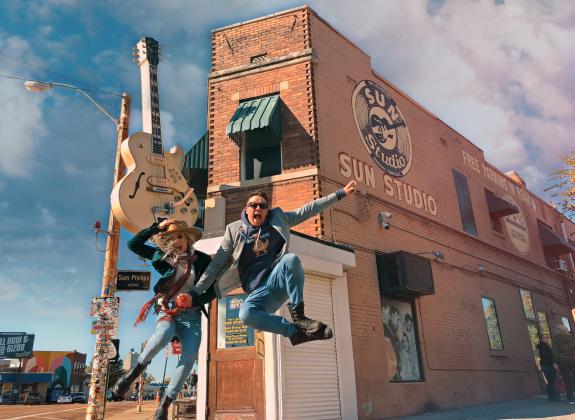 two people jump in the air in front of sun studio