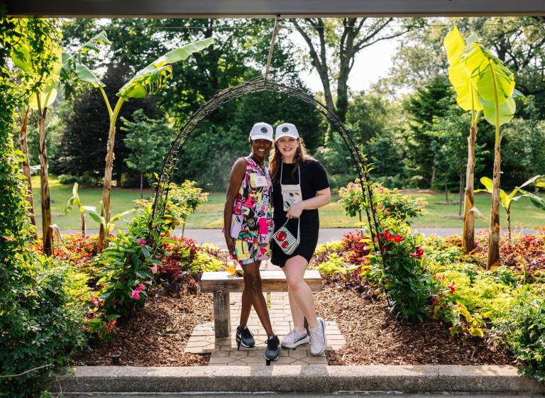 two women smile for photo in garden arch Photo