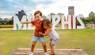 Kids pose in front of Memphis Sign on Mud Island