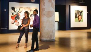Two people stand looking at pieces in Crosstown Concourse art gallery.