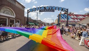 A massive pride flag being held up during th Pride Parade on Beale Street.