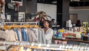 Girl shopping and sorting through clothing racks at a store