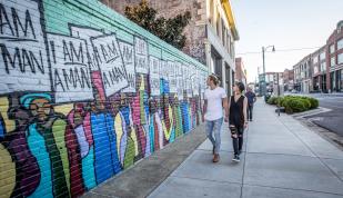 Couple walking by I Am A Man Mural on South Main Street.