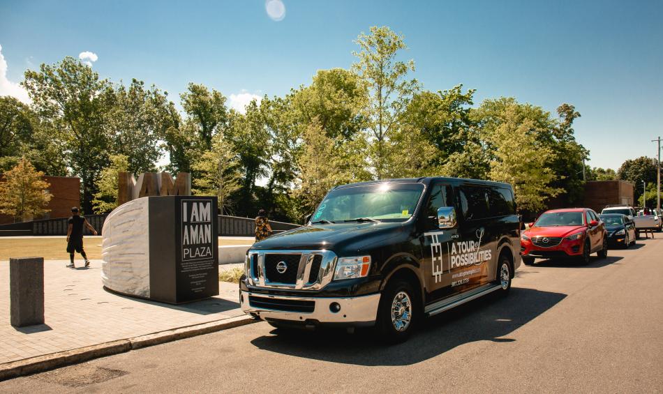 A Tour of Possibilities tour bus and caravan outside I Am A Man Plaza.