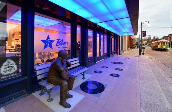 view of Blues Hall of Fame exterior with blue lights and Little Milton Statue