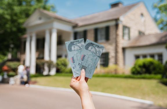 A tourist holds up admission tickets in front of the exterior of Graceland Mansion | Sean Fisher | Mr. Bootstraps