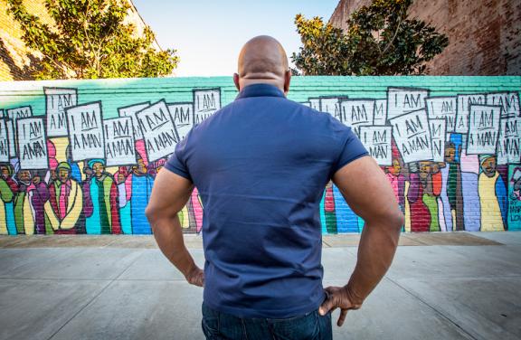 man facing the I AM Man Mural 