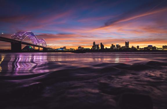 Hernando de Soto bridge over the Mississippi River at sunset with the Memphis Skyline in the background.