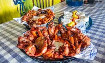 big platters of chicken wings on a blue checkered tablecloth