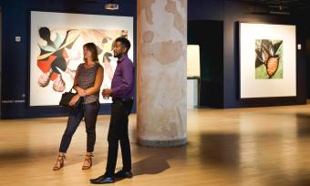 two people stand in Crosstown Concourse art gallery looking at pieces