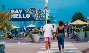 couple holds hand walking across the street in edge district