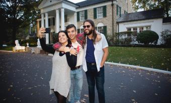 people pose for photo in front of graceland