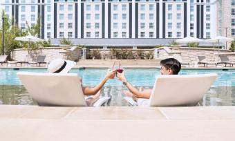 Couple tapping drink glasses together while lounging at the pool at Guesthouse at Graceland.