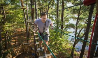 A man crosses a rope bridge at the Go Ape treetop adventure at Memphis' Shelby Farms Park