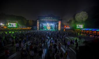 widest from far back showing music stage lit up at night and large crowd
